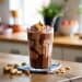 A creamy chocolate peanut butter smoothie in a clear glass