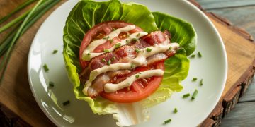 Keto BLT lettuce wraps on white plate with crispy bacon, fresh tomatoes, and butter lettuce cups drizzled with herb mayo